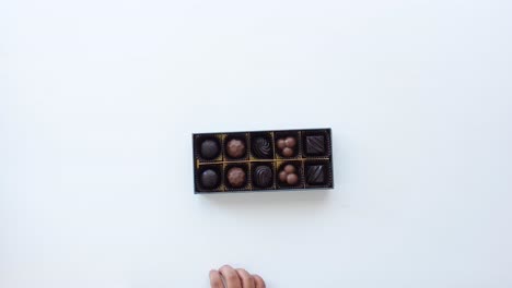 child's hand reaching into a box of chocolates