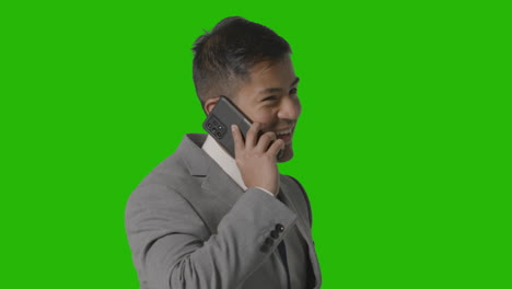 Studio-Shot-Of-Smiling-Businessman-In-Suit-Talking-On-Mobile-Phone-Against-Green-Screen-1