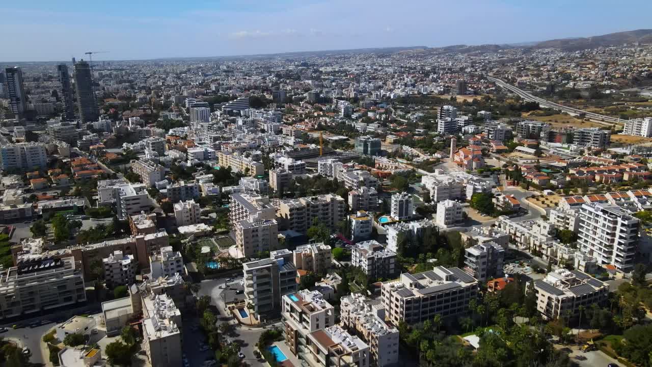 Drone video capturing Tirana's dense urban grid, showcasing a sprawling skyline under clear skies, with modern high-rises and traditional buildings bathed in natural light