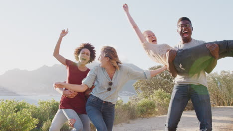 Männer,-Die-Frauen-Hochheben,-Während-Eine-Gruppe-Von-Freunden-Spaß-Gegen-Die-Flackernde-Sonne-Hat