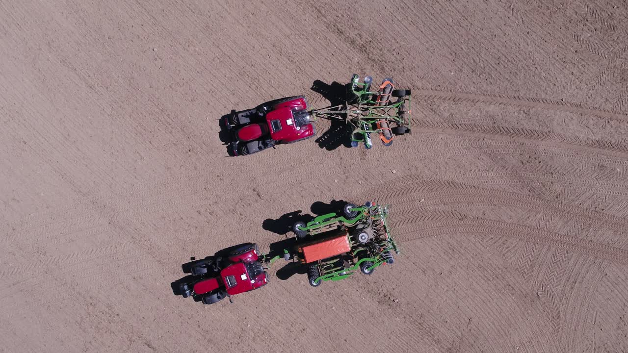 Overhead drone shot of two tractors moving apart in farmland near Prague on sunny day