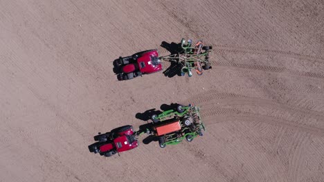 overhead drone shot of two tractors moving apart in farmland near prague on sunny day