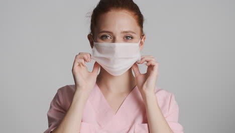 médico pelirrojo frente a la cámara sobre un fondo gris.