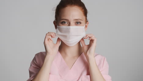 redheaded doctor in front of camera on gray background.