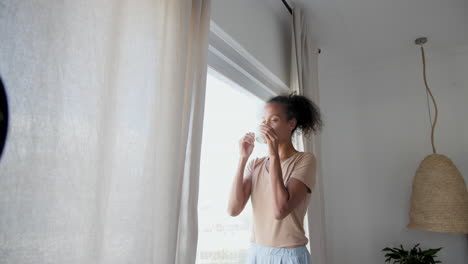 woman enjoying morning coffee, gazing out window at home, feeling relaxed