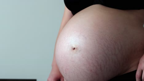woman in third trimester of pregnancy pulls maternity underwear over belly
