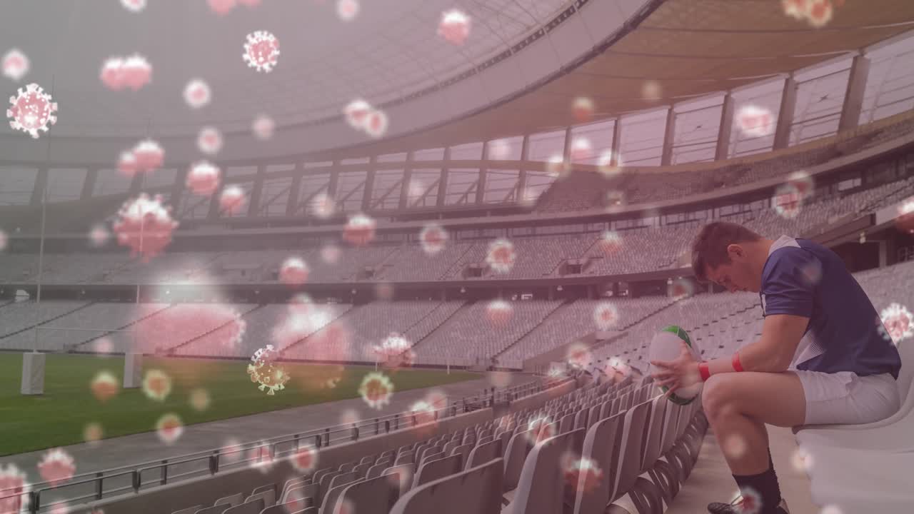 경기장의 관중석에 앉아 있는 럭비 공을 들고 있는 남성 럭비 선수에 대한 코로나19 세포