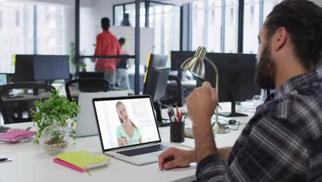 Middle-eastern-man-having-a-video-call-with-female-colleague-on-laptop-at-office