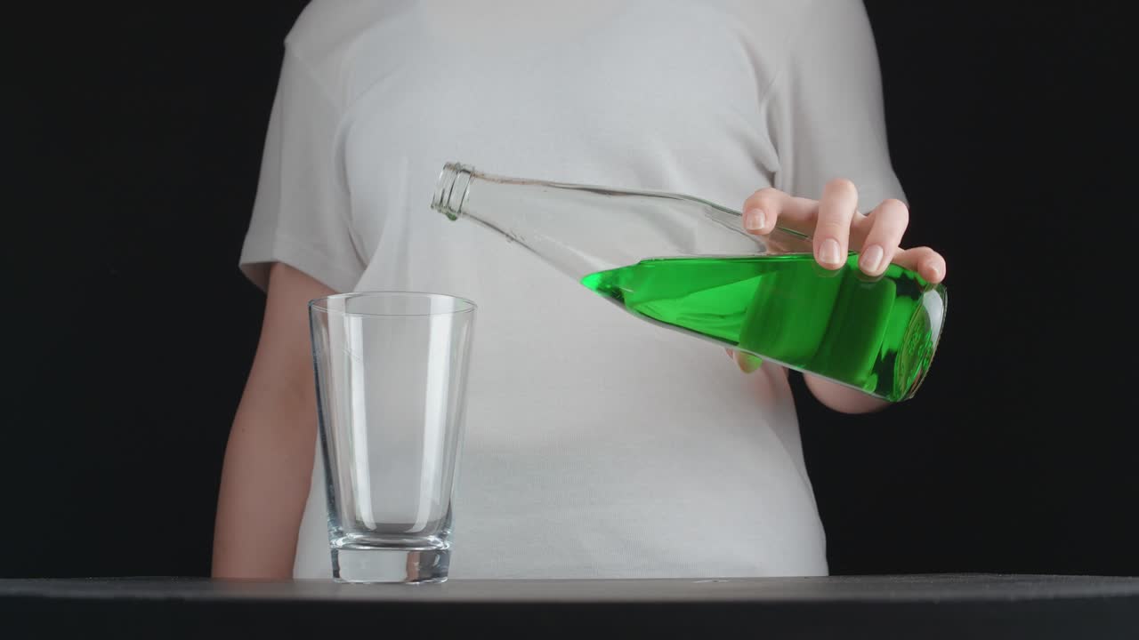 Shooting of young woman pouring green lemonade