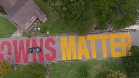 bird eye view of a large "black towns matter" sign painted on street in houston historical independence heights district