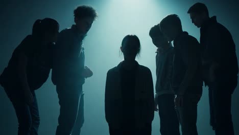 silhouettes of a group of young people in a dark and mysterious setting