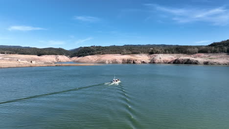 fisherman boat sailing on drying water reservoir in spain, aerial drone view