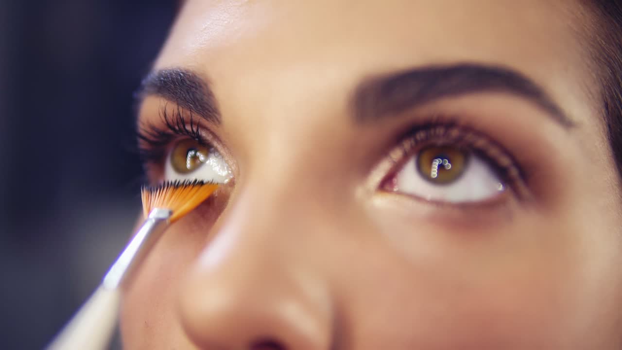 Professional make-up artist applying eyeshadow to model eye using special brush. Natural makeup in salon. Beauty, makeup and