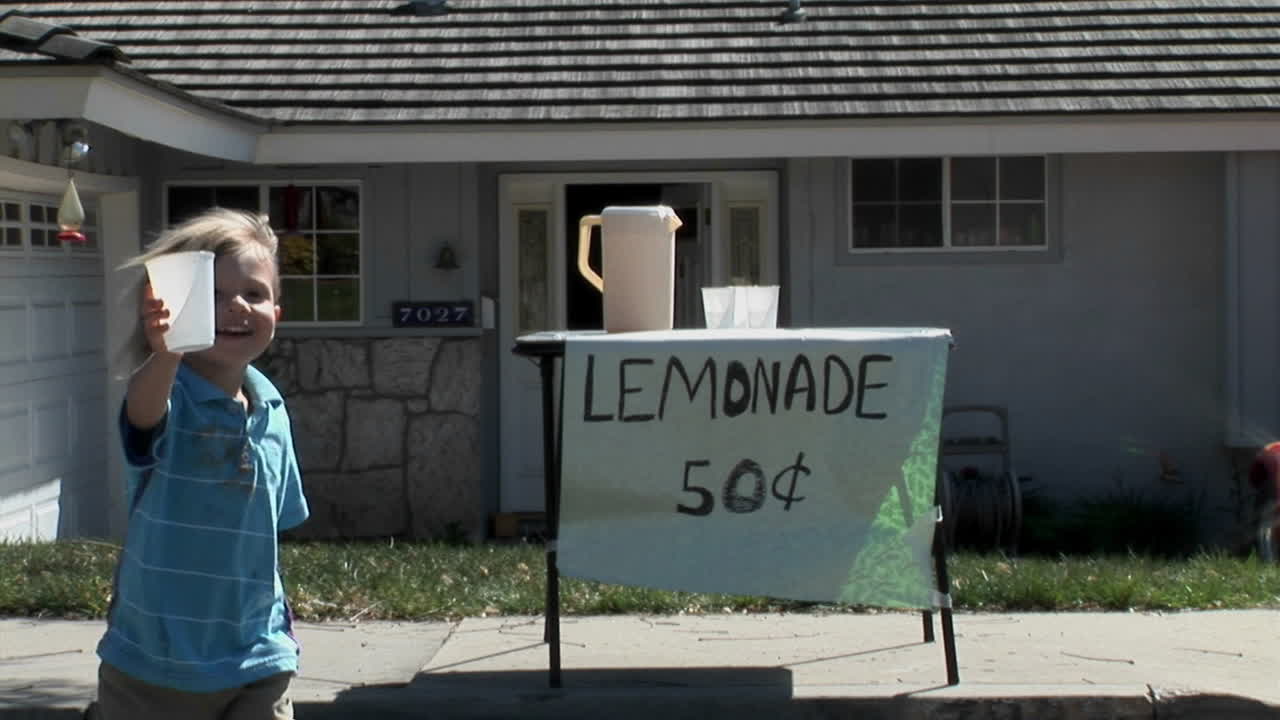 한 소년이 레모네이드 가판대에서 컵을 제공합니다