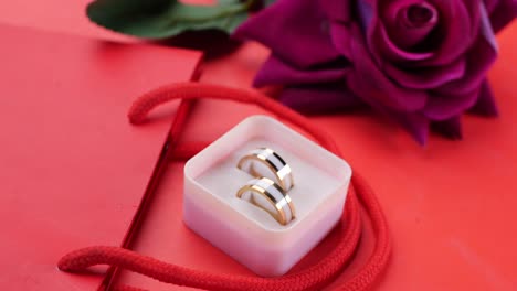 elegantes anillos de bodas en una caja de regalos con una rosa