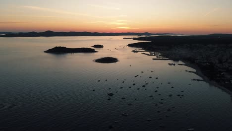 Panoramic-landscape-with-boats-in-marina-bay,-sea,-city-lights,-mountains,-blue-sky-at-dusk