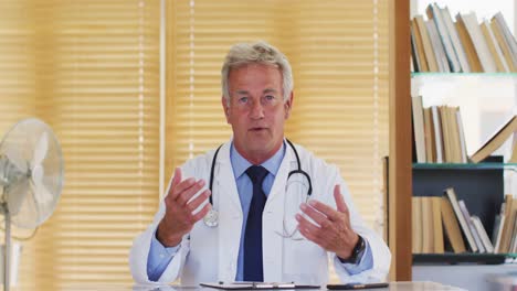 Portrait-of-male-caucasian-doctor-of-talking-looking-at-camera-while-sitting-in-hospital