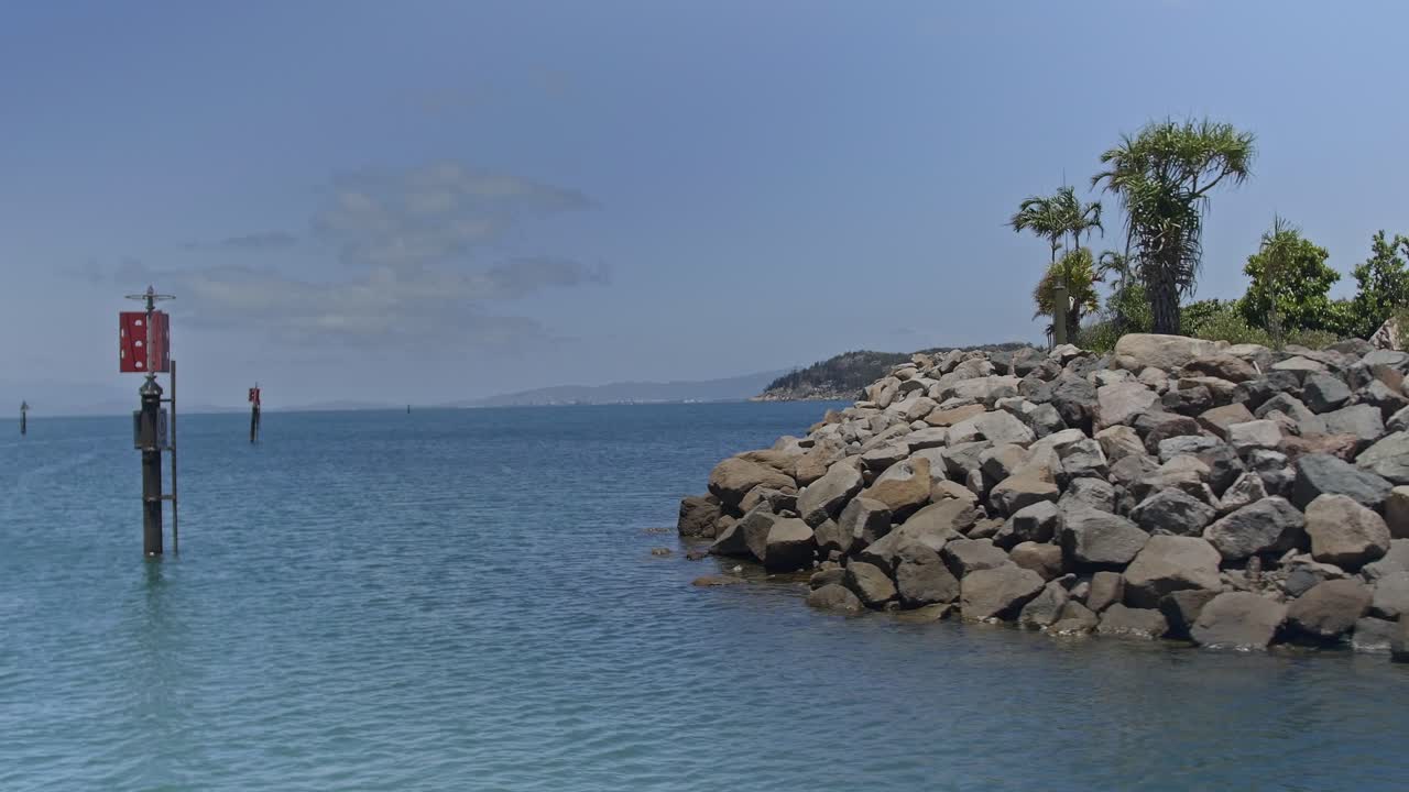 View from a barge departing an island marina with rocky bank surrounded by ocean