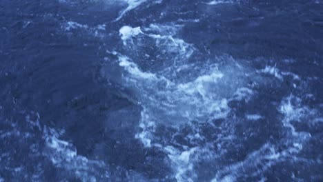 trailing water behind a boat sailing in the sea - high angle shot