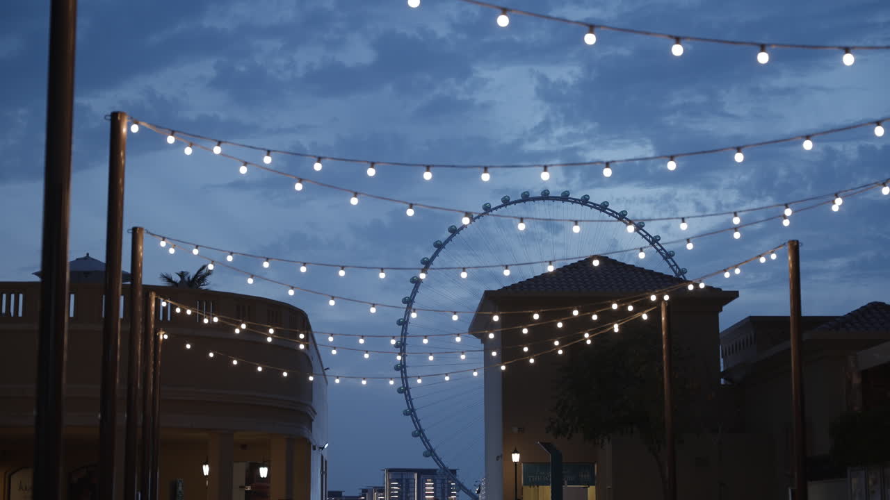 Evening view of a city street with Ferris wheel and string lights