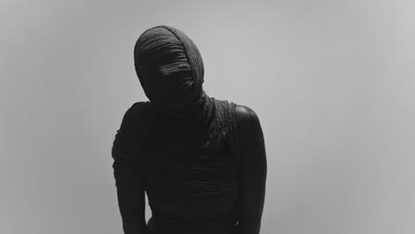 a mummy of a woman on a white backdrop moves her head