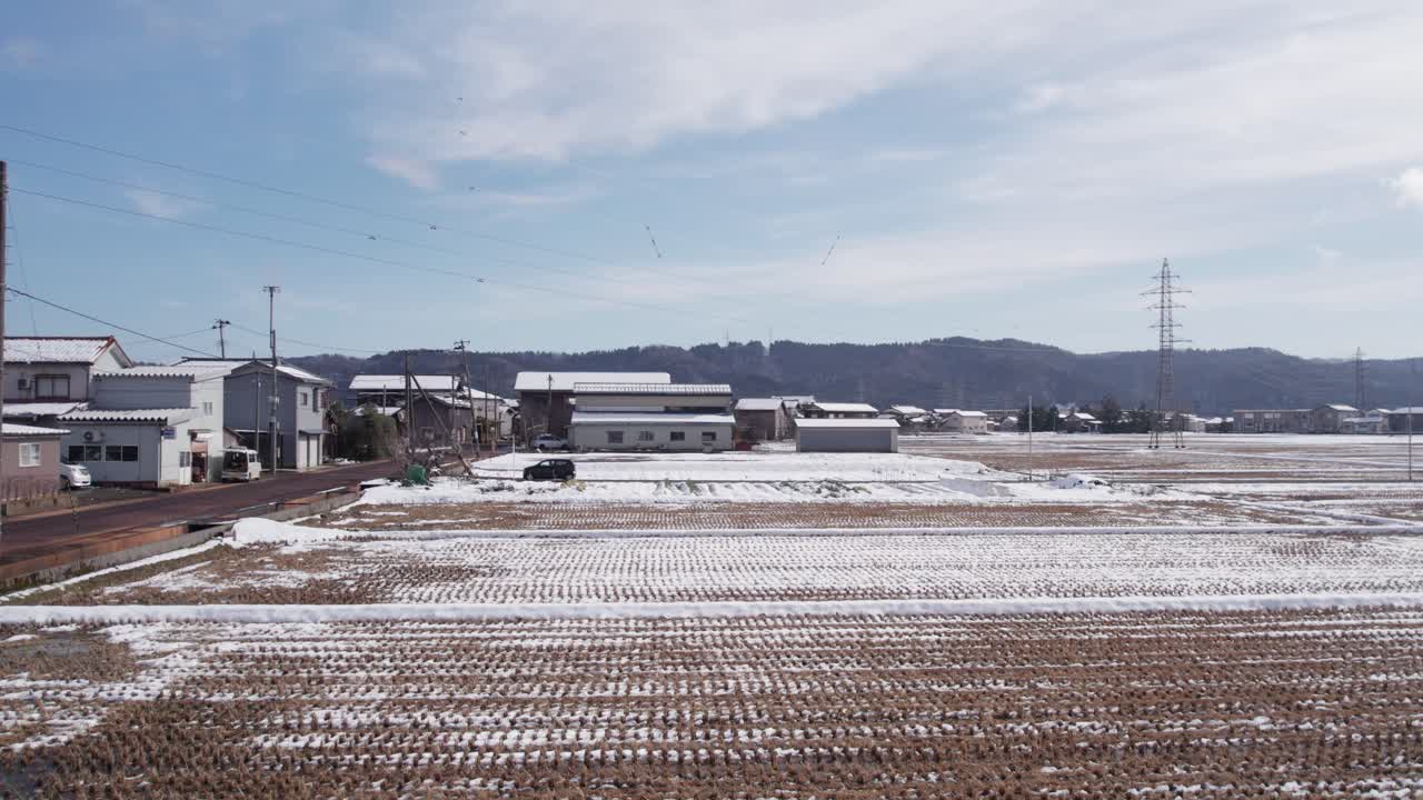 Winter footage showing a vehicle traveling through rural Japan surrounded by snow-covered rice fields