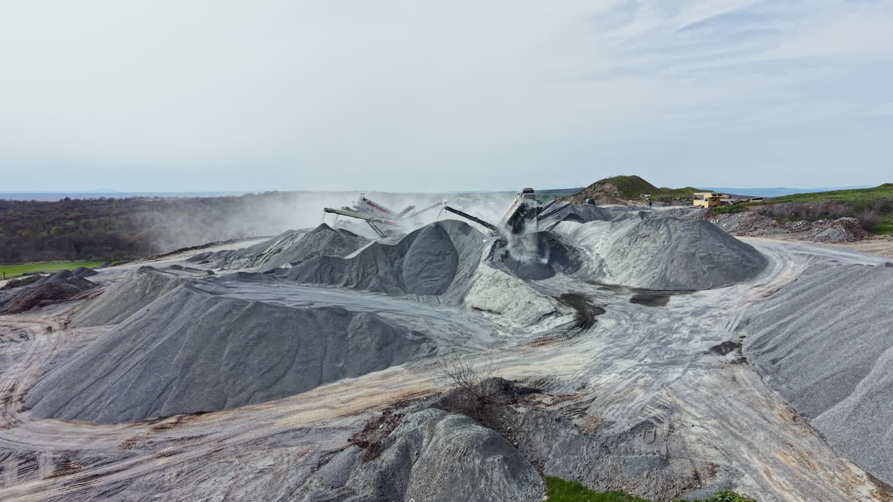 Granite quarry activity shows large rocks and machinery in a mining area during daylight in a remote location