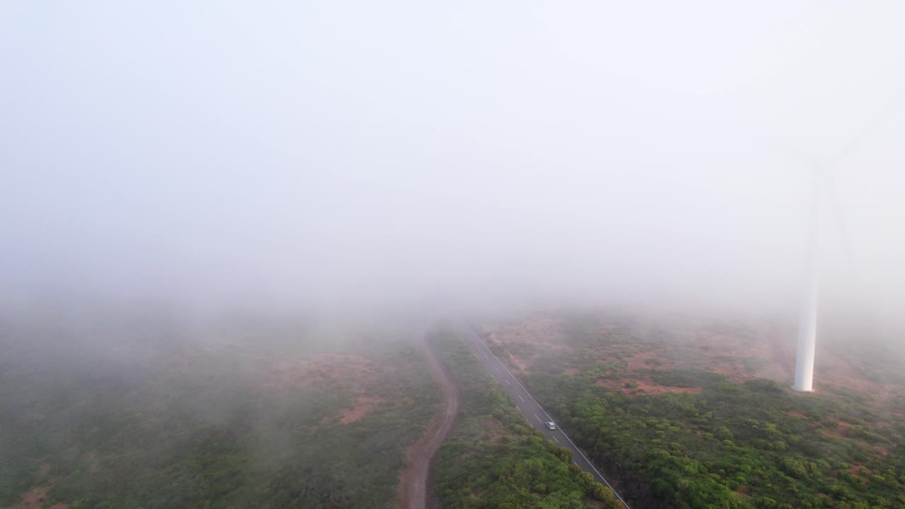 풍력 터빈 근처에서 운전하는 자동차의 공중 비행 흐린 안개