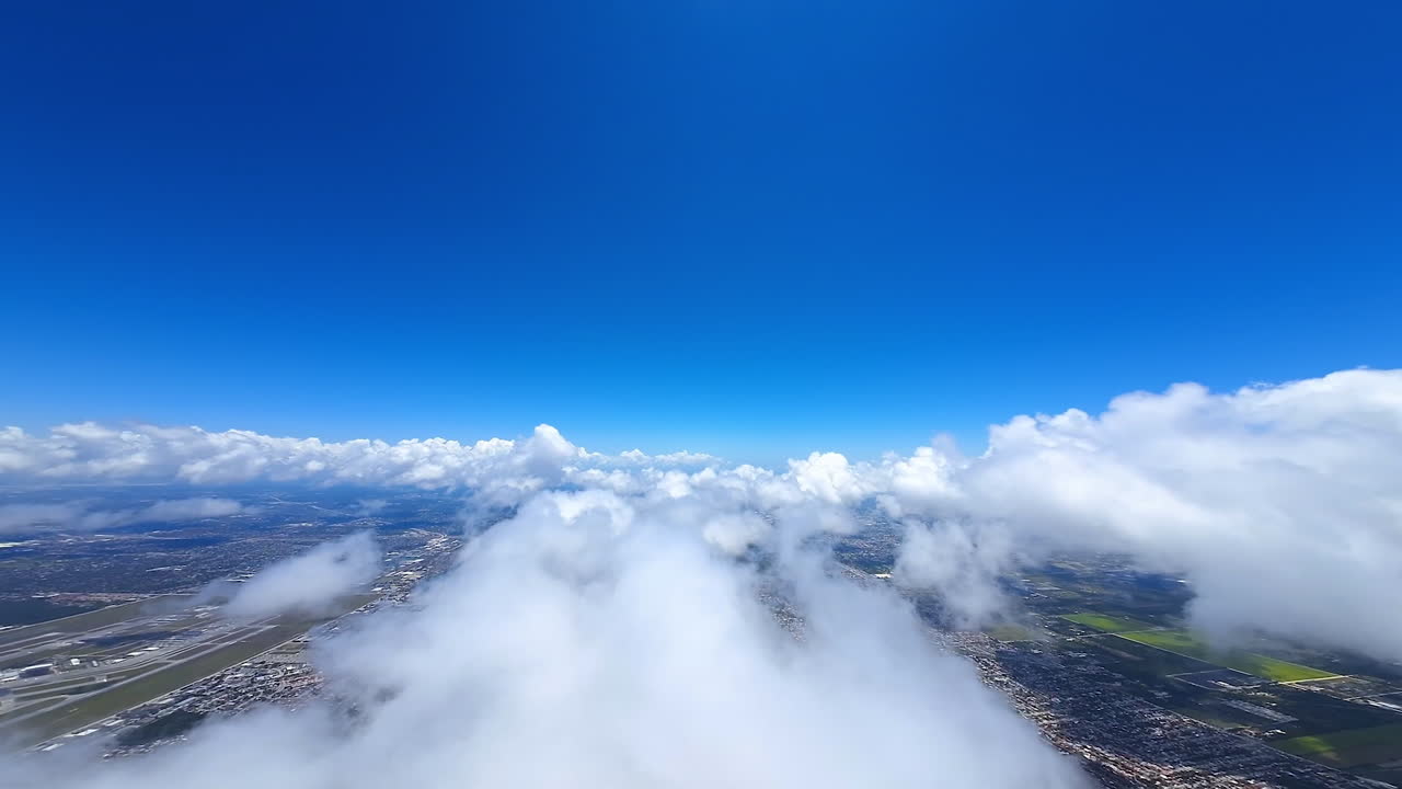 Exciting flight above the fluffy white cloudscape. Top view on the urban landscape of a huge metropolis. FPV drone footage.