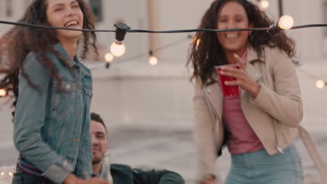 group of happy friends hanging out dancing together enjoying rooftop party at sunset drinking having fun on weekend celebration