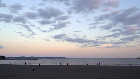 Amplia-Vista-Abierta-En-La-Hermosa-Playa-Al-Atardecer-Con-Nubes-Altas-Y-Luna-Y-Siluetas-De-Personas-Caminando-En-La-Arena---Vista-Bloqueada