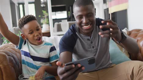 Video-De-Un-Feliz-Padre-E-Hijo-Afroamericanos-Sentados-En-El-Sofá-Y-Viendo-El-Partido-En-La-Televisión