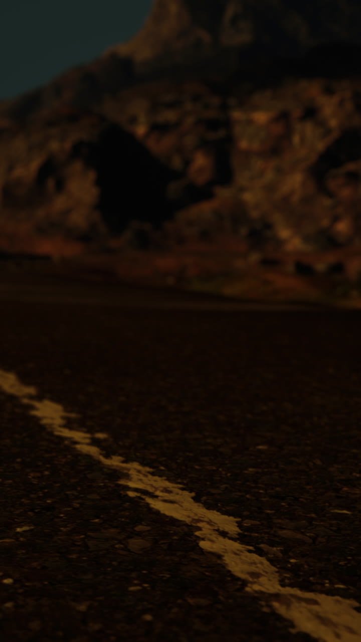 un camino largo y vacío que conduce a una cordillera al atardecer.