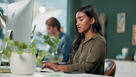woman experiencing neck pain while working at computer in office