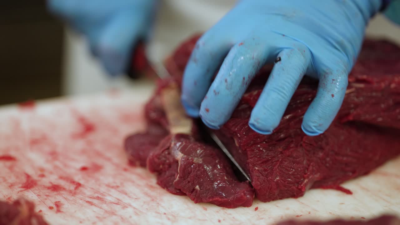 Skirt steak being separated by workers with a knife at a meat processing plant, Close up shot