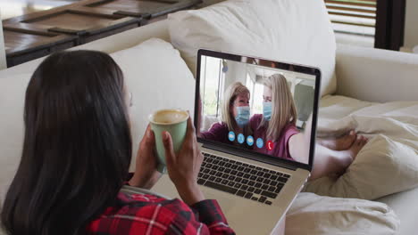 biracial woman on laptop video chat having coffee at home