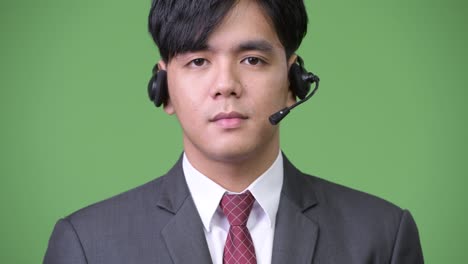 young handsome asian businessman working as call center representative