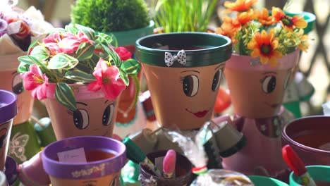 colorful flower pots with painted faces and vibrant flowers in an outdoor market display