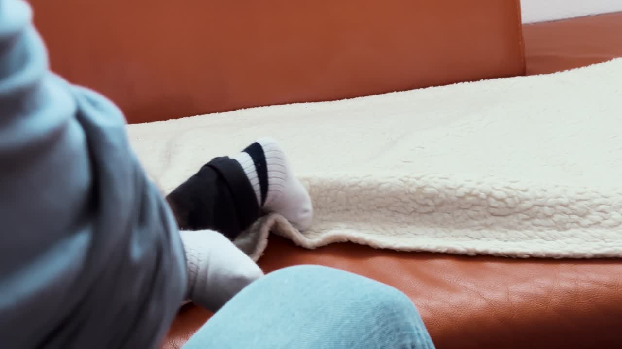 A small child moves and plays on a soft blanket on a couch, showing family life, childhood joy, and cozy home moments