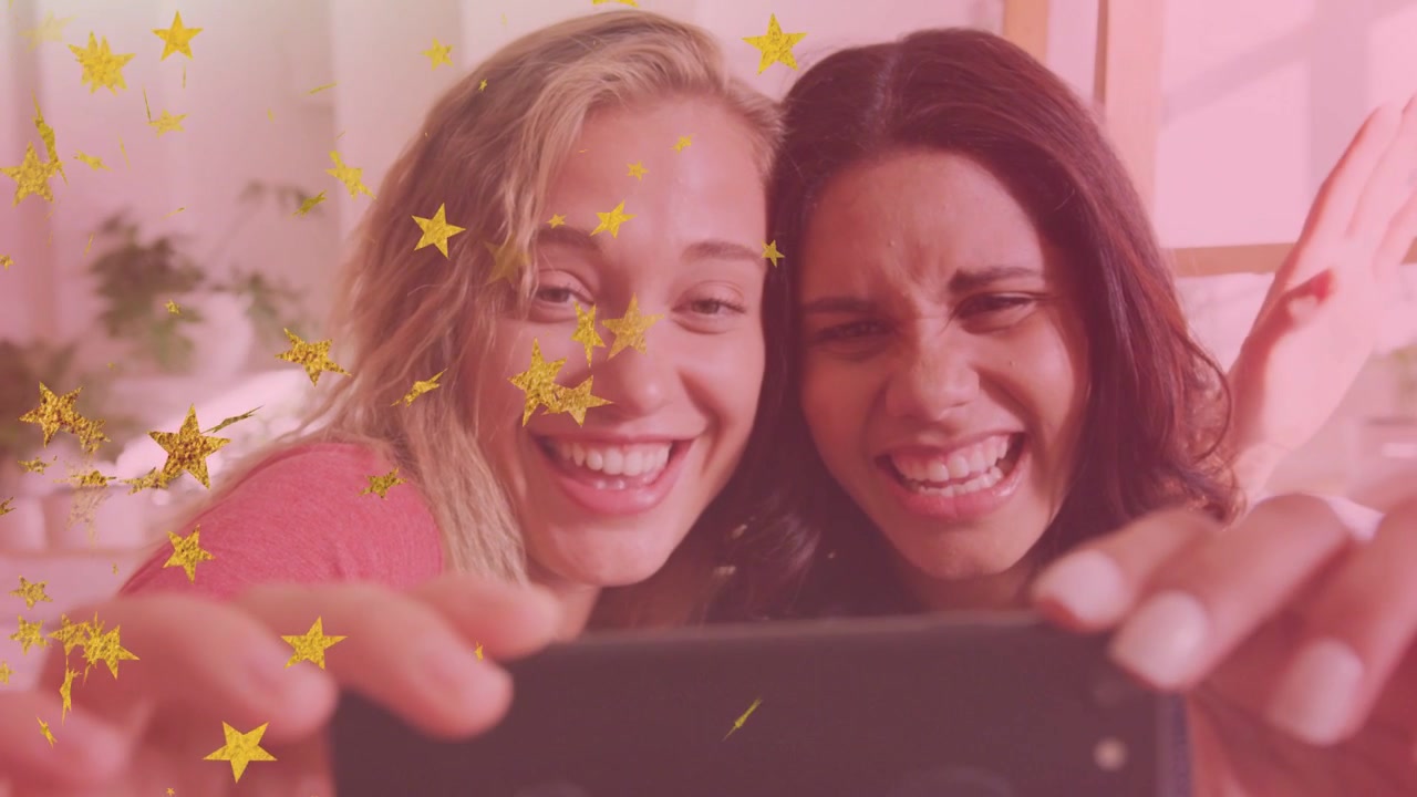 Duas mulheres inclinando o telefone tirando selfie social enquanto se inclinam, filtro de estrela dourada flutuando sobre os rostos