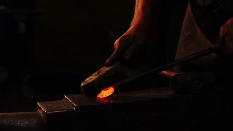 mid-section of blacksmith using wire brush on hot iron