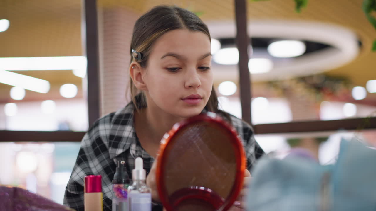 joven aplica suavemente el maquillaje mientras se mira en el espejo con una sonrisa suave, expresión enfocada, productos de belleza en la mesa, iluminación natural, resaltar el cuidado personal y la rutina de belleza