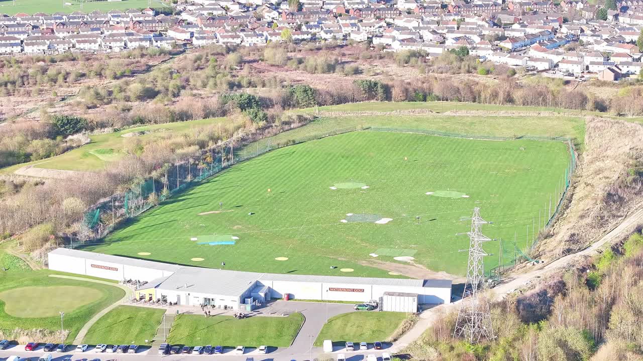 Wide rising aerial view of Waterfront Golf Club practice range in morning summer sunlight, Rotherham, Yorkshire, UK