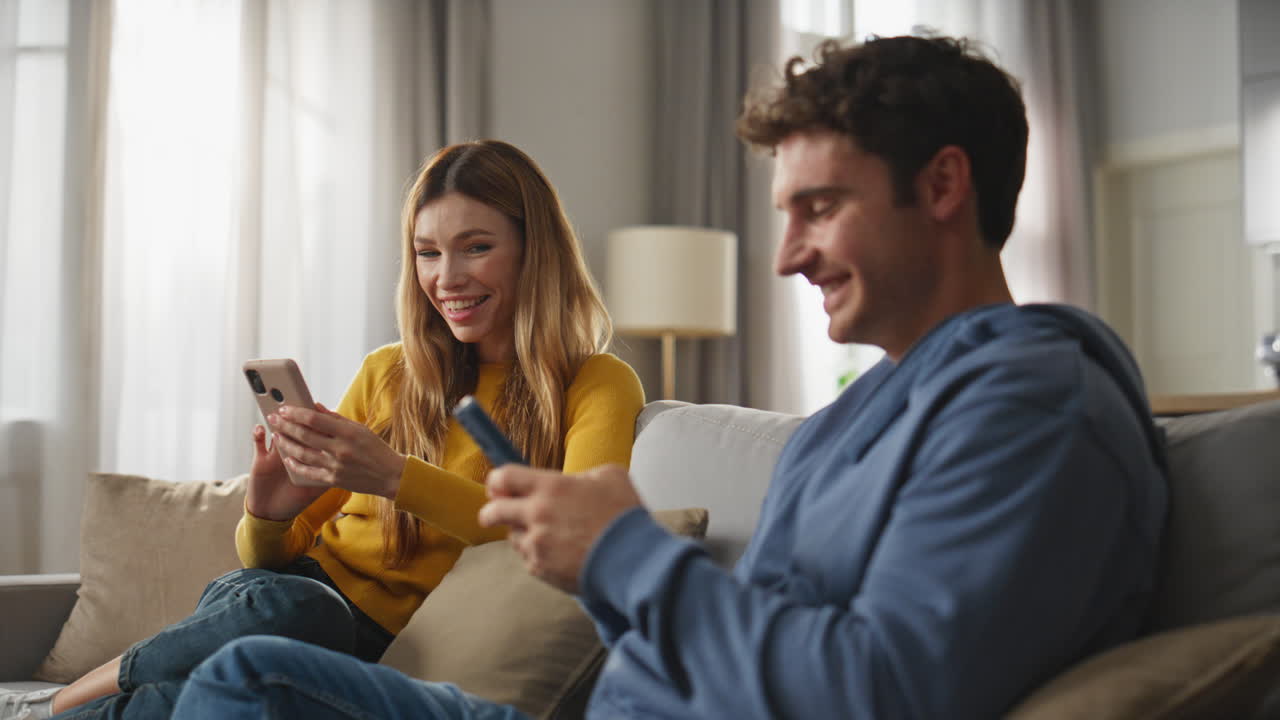 Closeup online couple smiling each other resting home. Man woman chatting phones