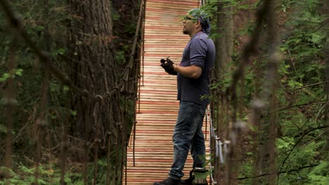 hombre en un puente colgante de madera en un bosque