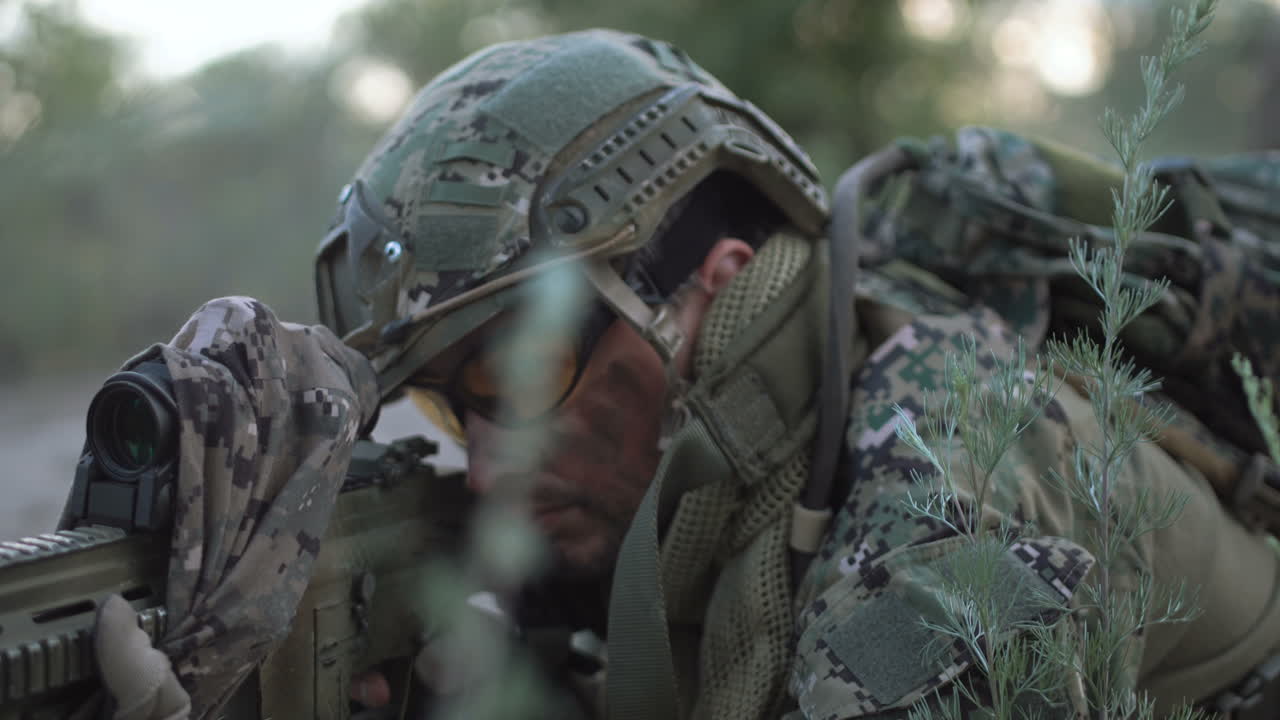 Soldier in camouflage looking through a scope in the woods