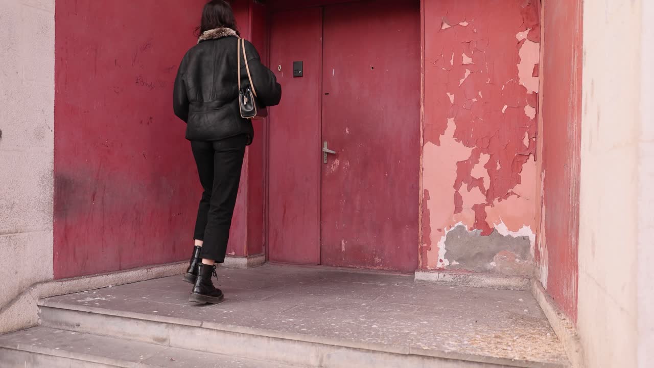 Woman walking up steps to a red door