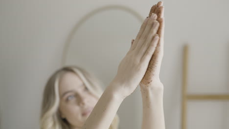 woman applying coffee scrub to hands