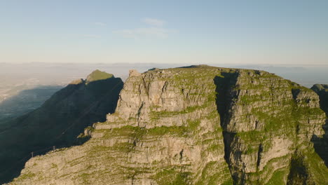 Slide-and-pan-footage-of-huge-rock-massif-of-famous-Table-mountain.-Bright-sun-shining-onto-sandstone-mountain.-Cape-Town,-South-Africa