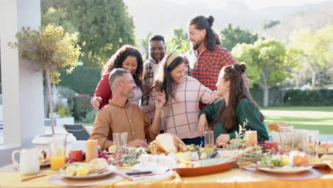 happy diverse male and female friends posing on thanksgiving celebration meal in sunny garden